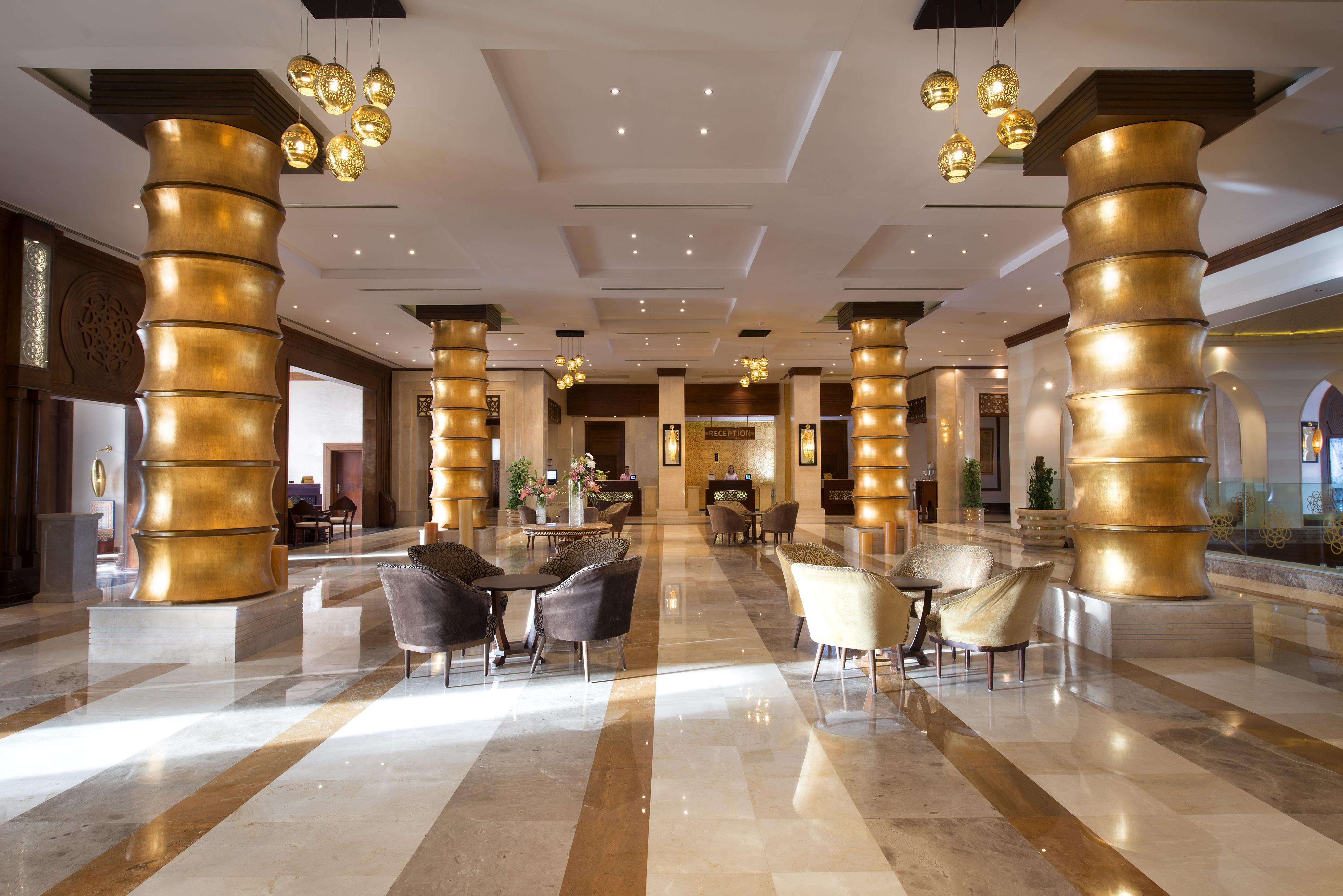 Sunrise Arabian Beach Resort Sharm el-Sheikh Exteriör bild The photo shows a spacious hotel lobby with elegant decor. There are tall, golden columns that create a striking visual effect. The floor features a mix of light and dark marble tiles, adding to the luxurious ambiance. A variety of seating is arrange